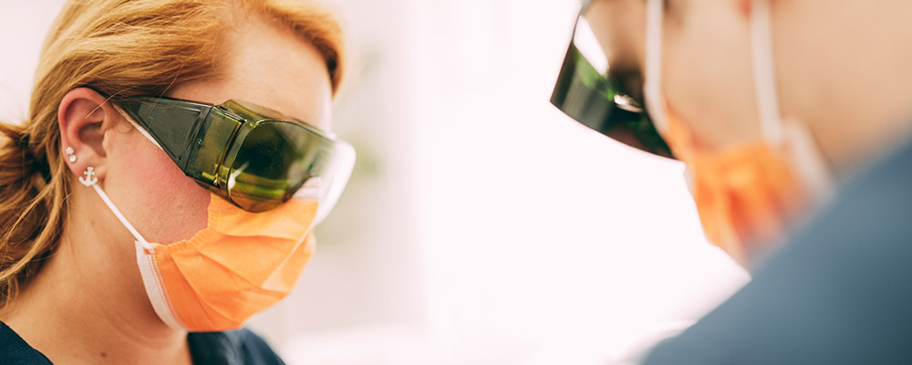 Helferin und Zahnarzt tragen Schutzbrillen bei der Laserbehandlung in Berlin-Spandau. 