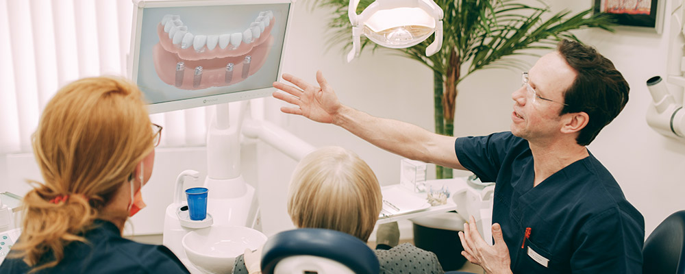 Dr. Sven Kurth zeigt Patientin die Vorteile einer Behandlung mit Zahnersatz auf Implantaten. 